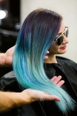 Fototapeta premium Stylist demonstrates his work with Beautiful girl. Barber haircut dyed hair color blue