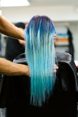 Fototapeta premium A girl with dyed hair sitting in a chair at the beauty salon studio. Work over the demonstration.