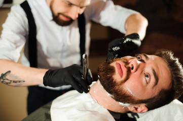 Fototapeta premium Master cuts hair and beard of men in the barbershop