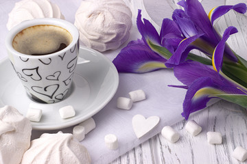 Still life with cup of coffe marshmallow zephyr iris flowers heart sign on white wooden background. Wedding. Valentines Day. Womans Day. 8 march