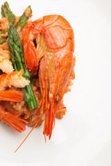 rice in tomato sauce with prawns, asparagus and cauliflower close-up on a plate.