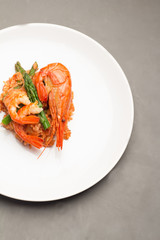 rice in tomato sauce with shrimp, cauliflower and asparagus on a white plate top view.