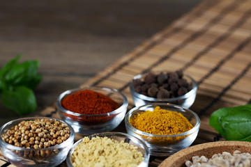 Various spices in bowls with fresh seasoning on rustic wooden background, closeup