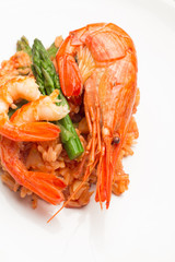 rice in tomato sauce with shrimp and asparagus on a plate close-up.