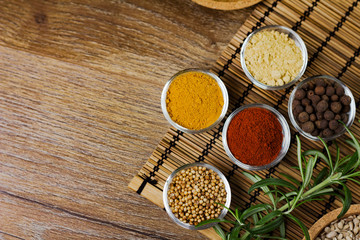 Various spices in bowls with fresh seasoning on rustic wooden background, top view
