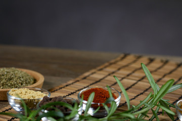 Various spices in bowls with fresh seasoning on rustic wooden background, closeup
