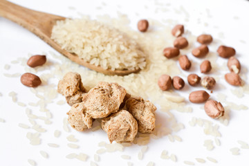 soy meat and a spoon with uncooked rice close-up, studio shot on white