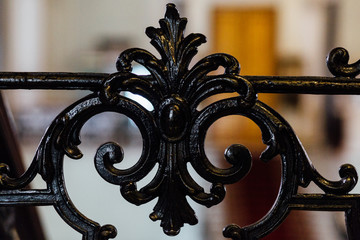 Vintage old black wrought-iron openwork railing staircase or fence. The fragment part. Forging, handmade. Palace interior