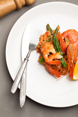 rice with shrimp and asparagus on a white plate with cutlery top view on gray background.