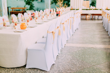 Decorative White Mantles And Colored Ribbons On Chairs At Festive Table.