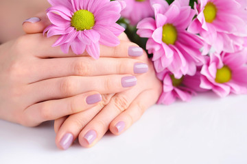 Obraz na płótnie Canvas Hands of a woman with pink manicure on nails and pink flowers