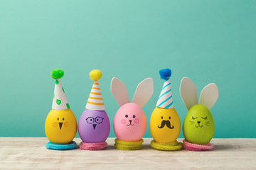 Fototapeta premium Easter holiday concept with cute handmade eggs, bunny, chicks and party hats