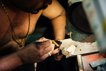 Kerala, India - February, 2016: Man working in gold smith factory. Process of engraving gold in...