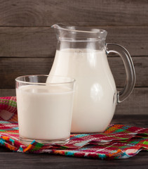 jug and glass of milk on a wooden background