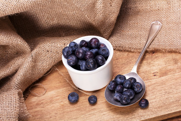 Pot of blueberries with spoon on a rustic background