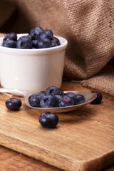 Pot of blueberries with spoon on a rustic background