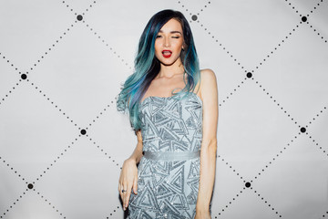 Beautiful sexy celebrity girl posing for press photographers. Elegant dress, long hair dyed blue.