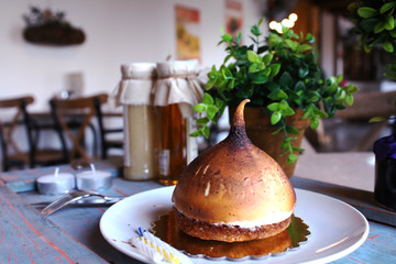 Airy meringue Cake in the shape of a cone on a white plate. candles and green plants in the background.