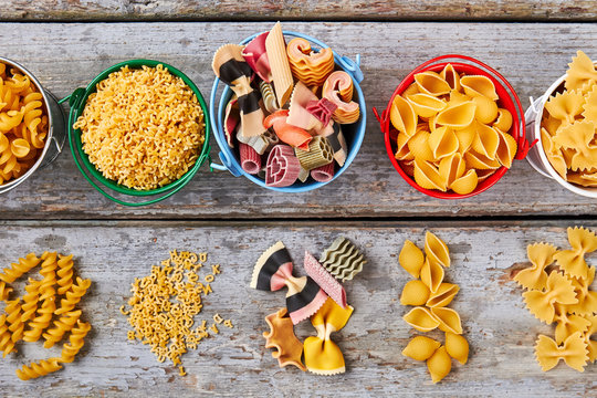 Many different kinds of pasta in colorful buckets.