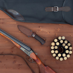 Hunting season. Leather carrying case, holster, gun, bullet, cartridge, knife on a wooden background. Top view.