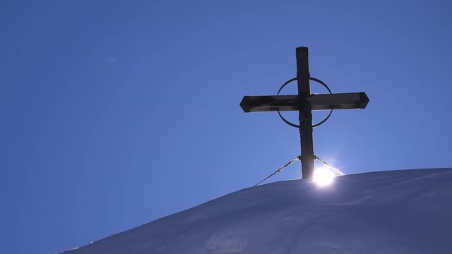 Wooden cross on top of snow covered hill, time lapse footage of setting sun