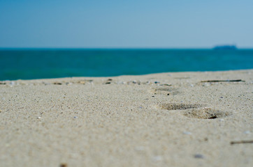 Fototapeta na wymiar Footprints on the sandy coast and soft, blue background