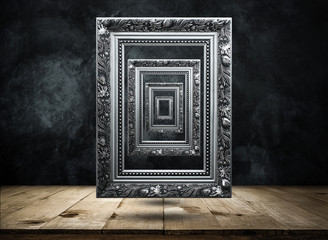 silver Antique picture Frame on dark grunge wall with Wooden table top mysterious, confused,...