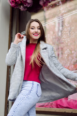 Outdoor portrait of a young beautiful happy smiling woman posing on the street wearing cashmere sweater and coat, looking at the camera. 