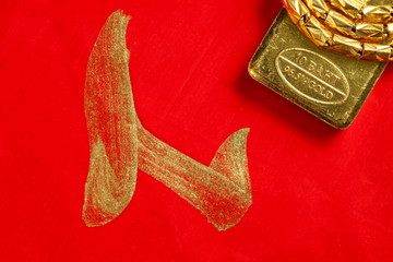 The gold bar put on the red color paper with chinese letter written from chinese brush as a background  represent the wishes concept related idea.