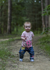 Little cute baby make his first steps on the forest road.