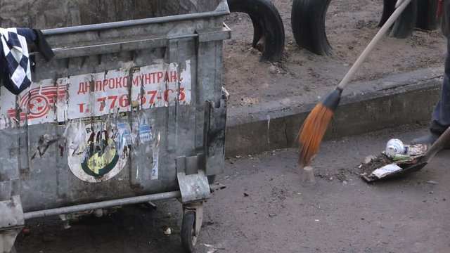 Janitor broom sweeps debris on the shovel