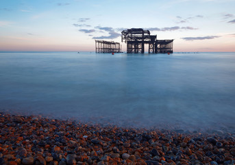 Abandoned West pier in Brighton at sunset, warm blue and red colors