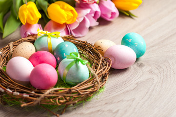 Easter composition of the branches, cakes, tulips colored eggs cooked for the holiday on the wooden background 