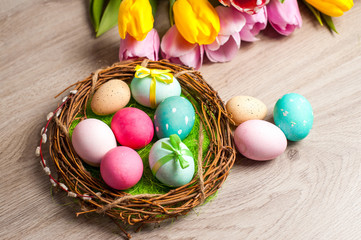 Easter composition of the branches, cakes, tulips colored eggs cooked for the holiday on the wooden background 