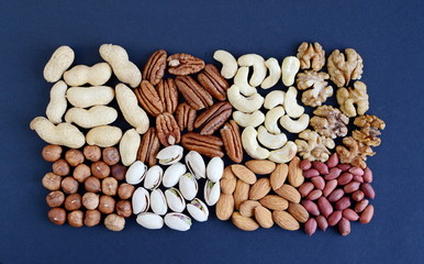 Assorted mixed nuts, peanuts, almonds, walnuts, cashew nuts, hazelnuts, pistachios, pecan nuts. Black background