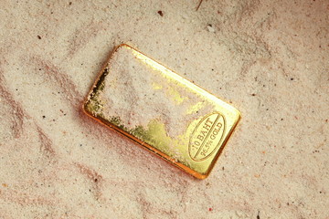 The gold bar put on the sand background represent treasure and business finance concept related...