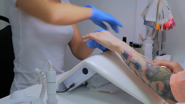 Preparing nail to manicure, master use special spray gor client nails in salon
