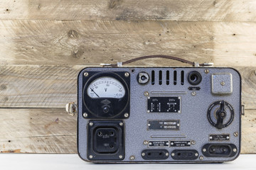 Old vintage electric stabilizer on weathered wooden background. Retro voltage regulator