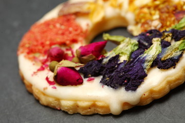 The cookie with flower topping put on slate board represent the bakery and pastry concept related idea.