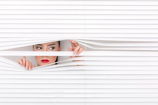 Portrait of a woman looking through out the blinds