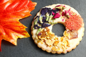 The cookie with flower topping put on slate board represent the bakery and pastry concept related...