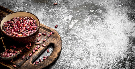 Fototapeta na wymiar red beans in a bowl on the old Board. On rustic background.