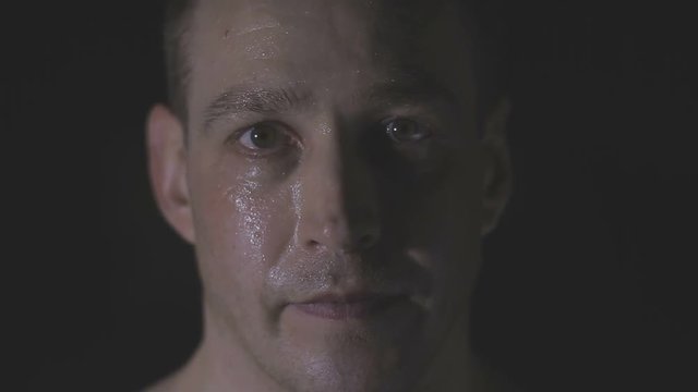 Intense sweaty face of young muscular man pulling rope