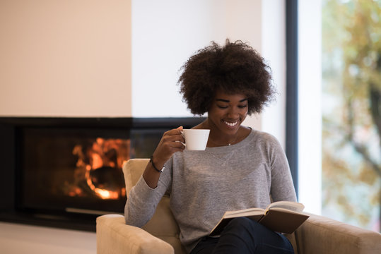 black woman reading book  in front of fireplace