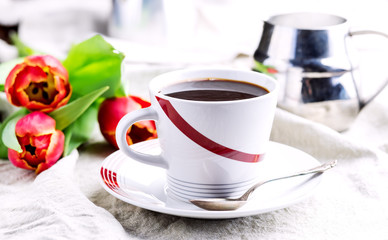 Fototapeta na wymiar Cup of fresh coffee onl linen napkins Tulips next to cup