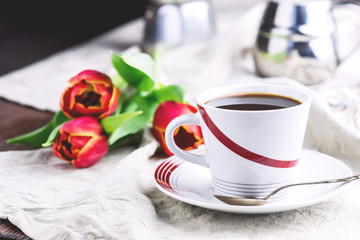 Cup of fresh coffee onl linen napkins Tulips next to cup