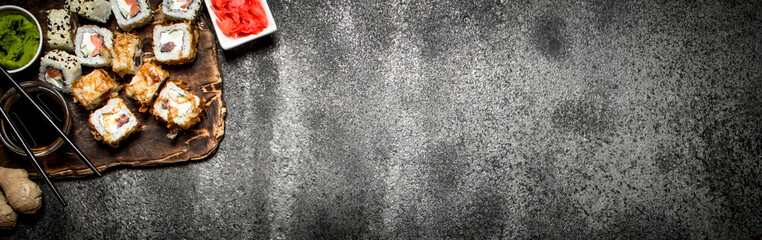 Japanese food. Sushi and rolls fresh seafood with soy sauce and pickled ginger. On rustic background.