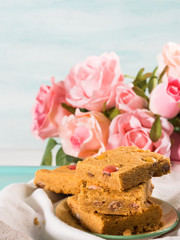 Festive breakfast set pastel color tray. Flowers roses Valentine's Mother day home made baked treat with candies. Peanut butter blonde bownies.