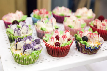 Delicious cupcakes with buttercream and fruits