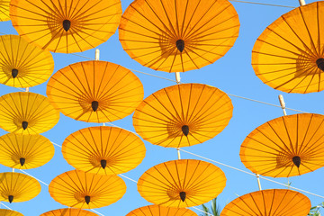 Fototapeta na wymiar yellow paper umbrella floating in the blue sky